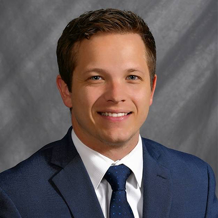Portrait of Mason Clark wearing dark blue jacket, tie and white shirt.