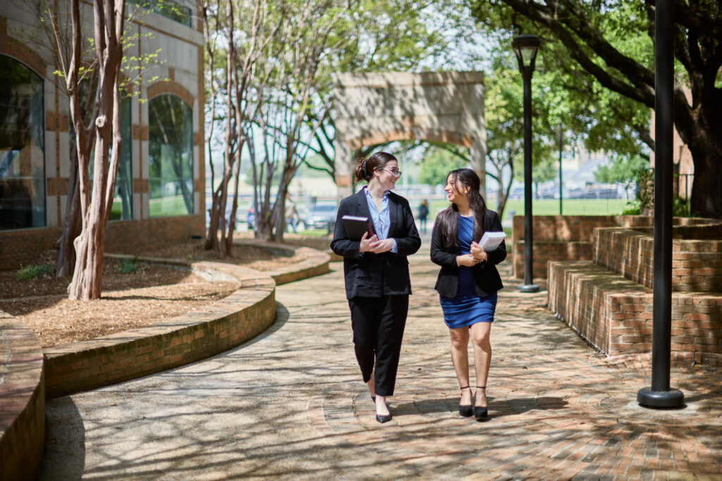 Two law students walking on campus and smiling