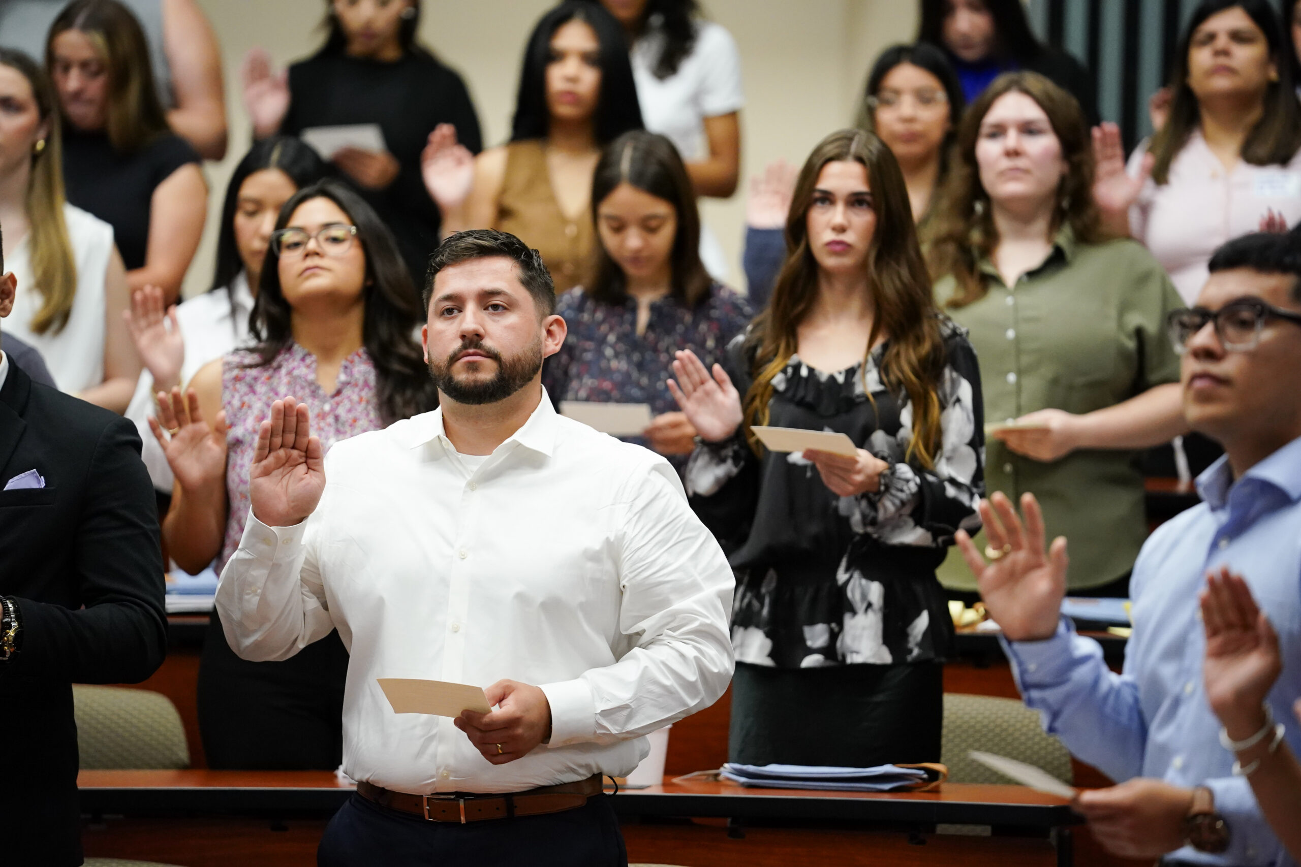 Students raise their hands in the law court room as they take the pledge.
