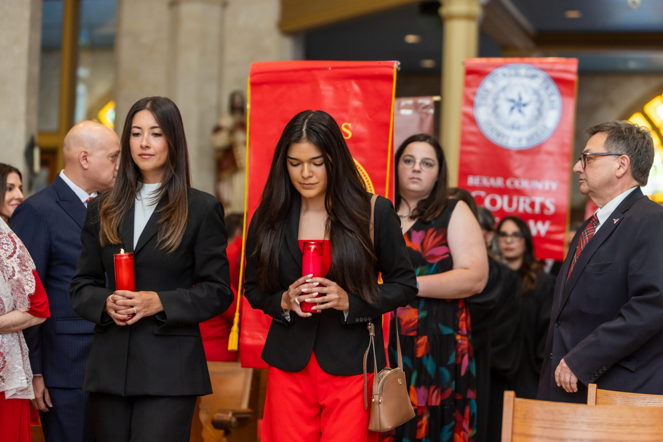 Students wearing Red, holding candles, walking down the aisle during Red Mass.